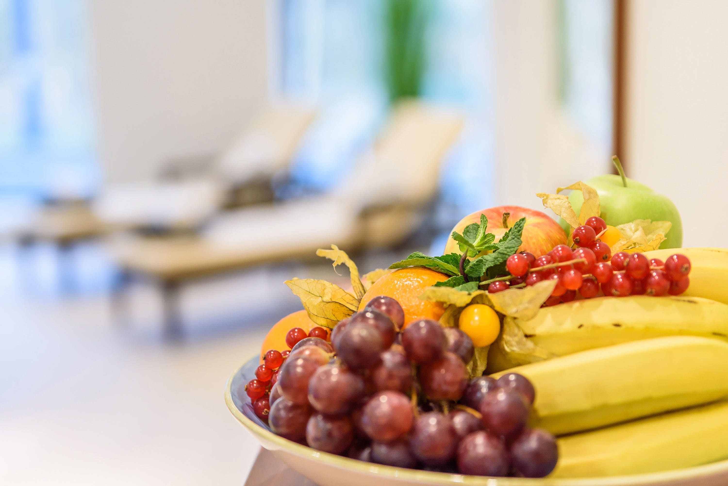 Eine Obstplatte mit Trauben, Bananen und Beeren auf einem Tisch in einem Hotelzimmer.