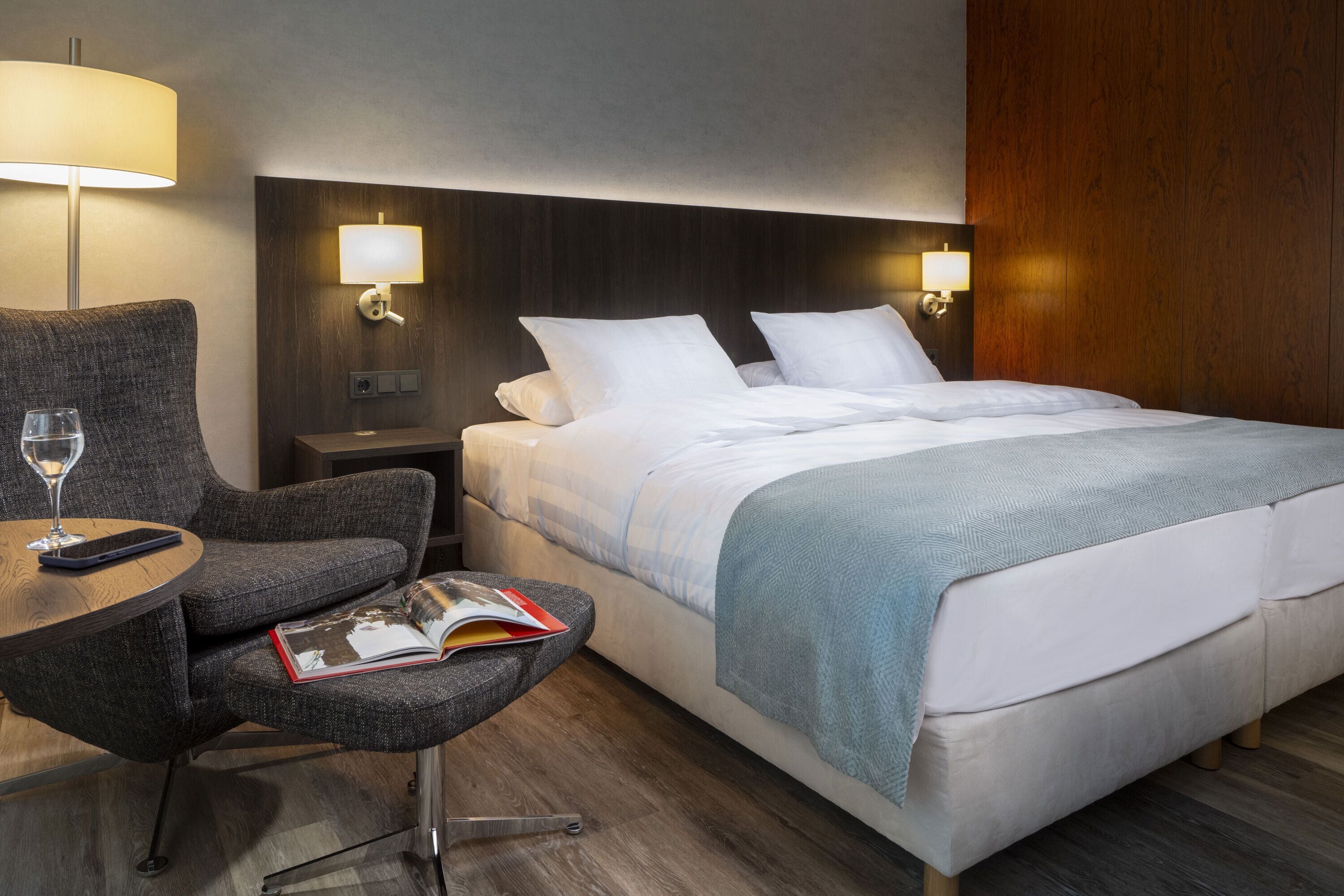 Une chambre d’hôtel avec un lit, une chaise, une table et une lampe.