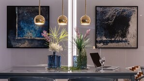 A modern dining area with a glass table, blue vases with plants, and a laptop. - Maritim Hotel Bremen (Bremen)