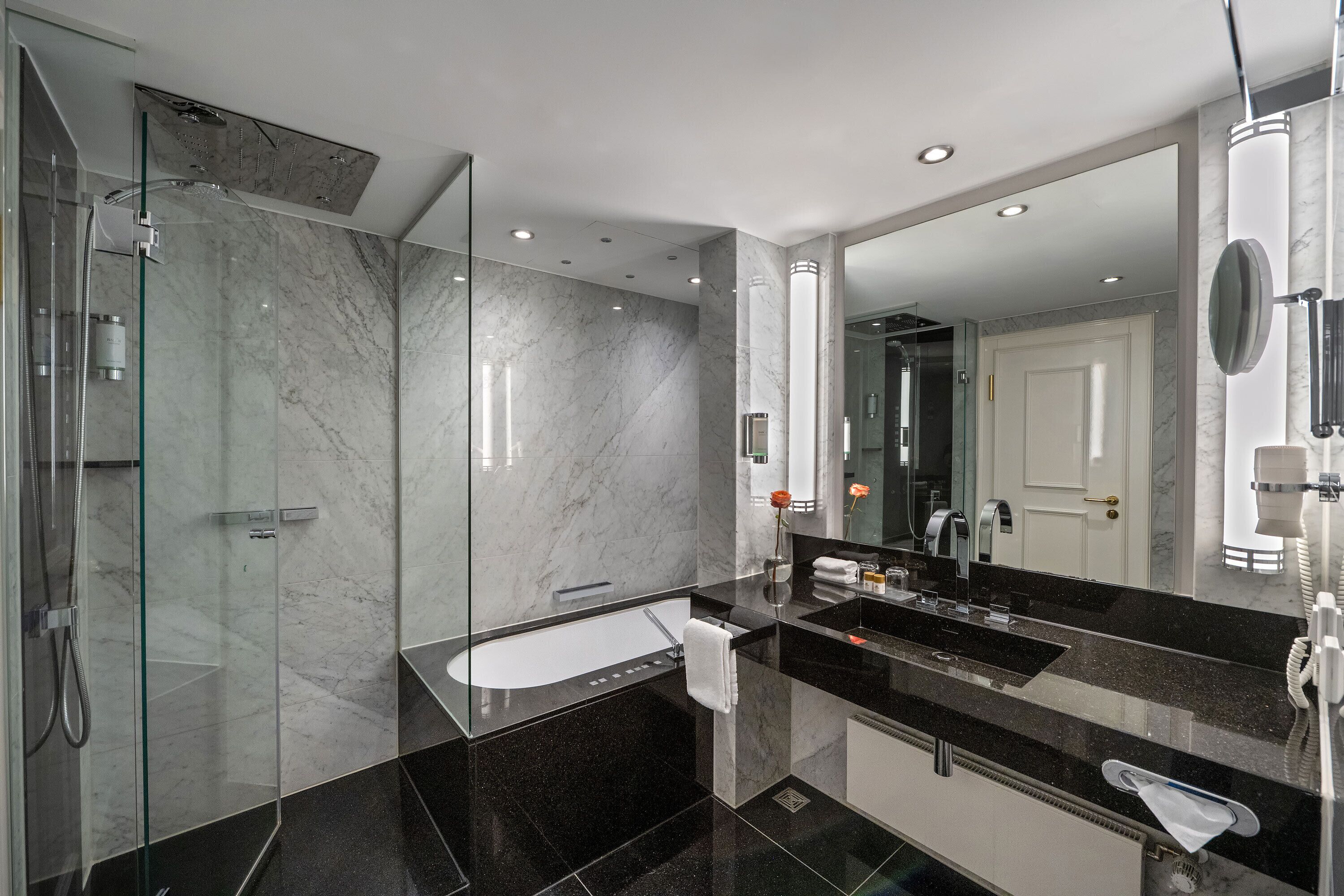 A modern bathroom with a glass-enclosed shower, a large mirror, and a black countertop sink.