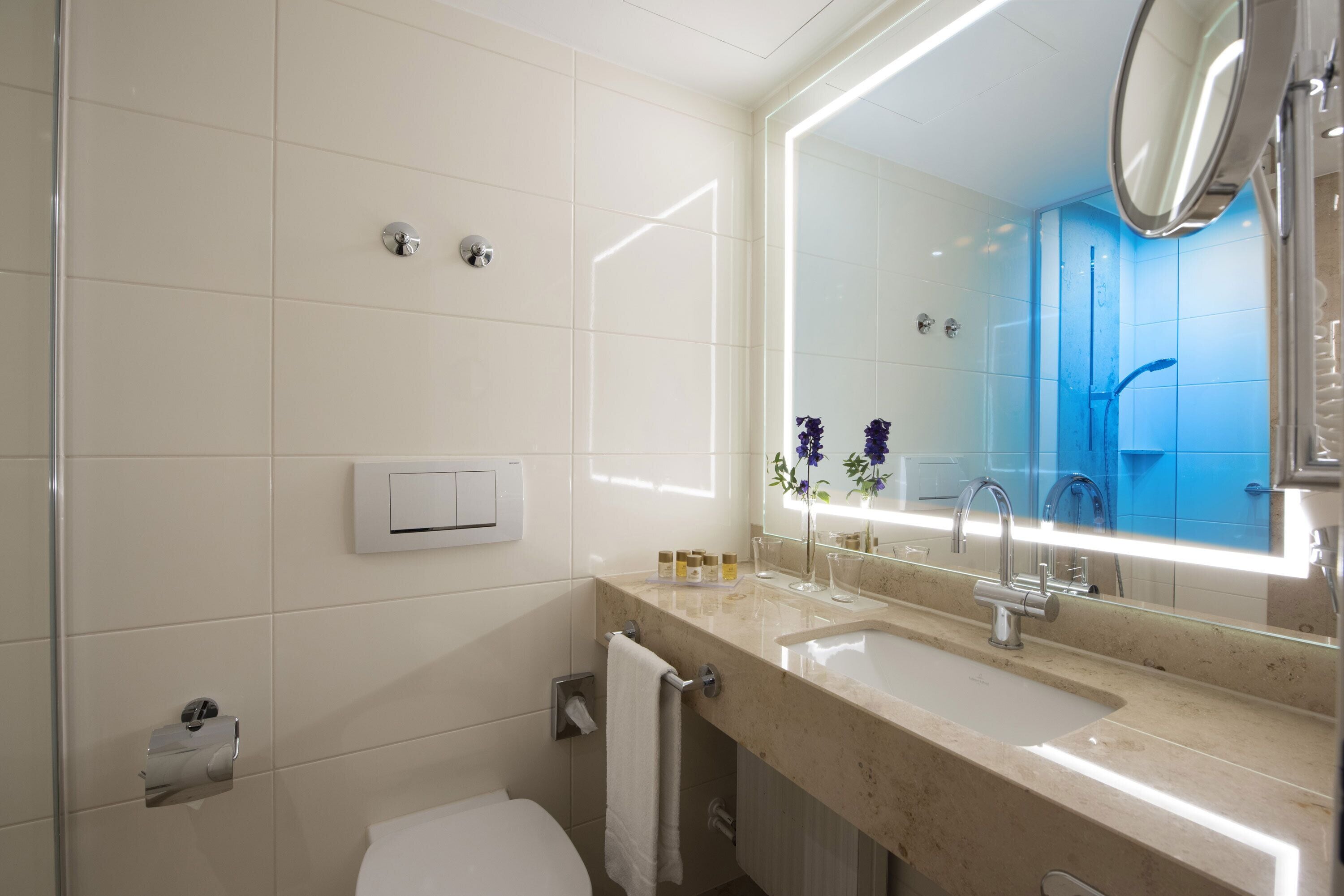 Een moderne badkamer met een grote spiegel, een wastafel en een toilet.