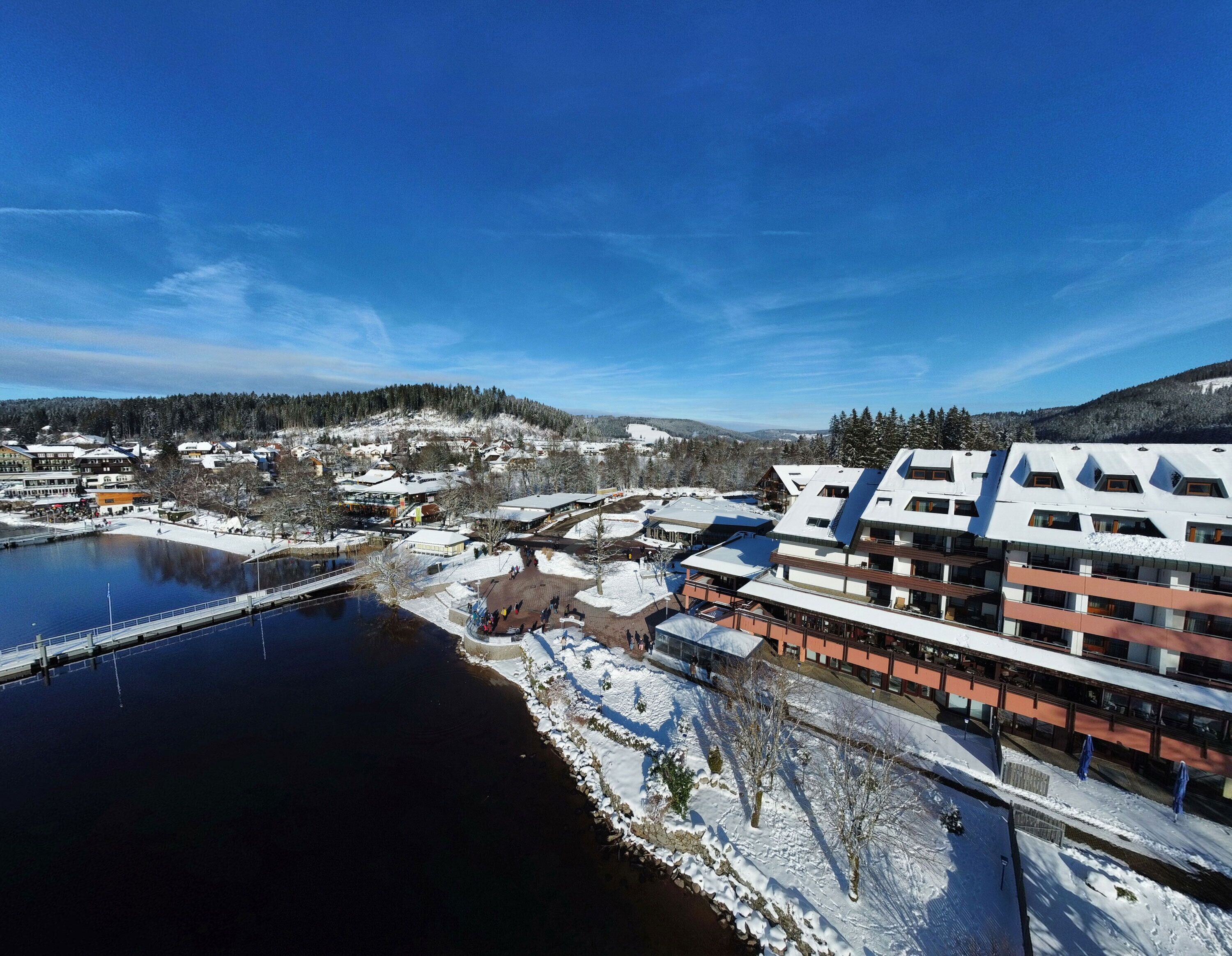 Escena invernal con un río, edificios cubiertos de nieve y un puente.
