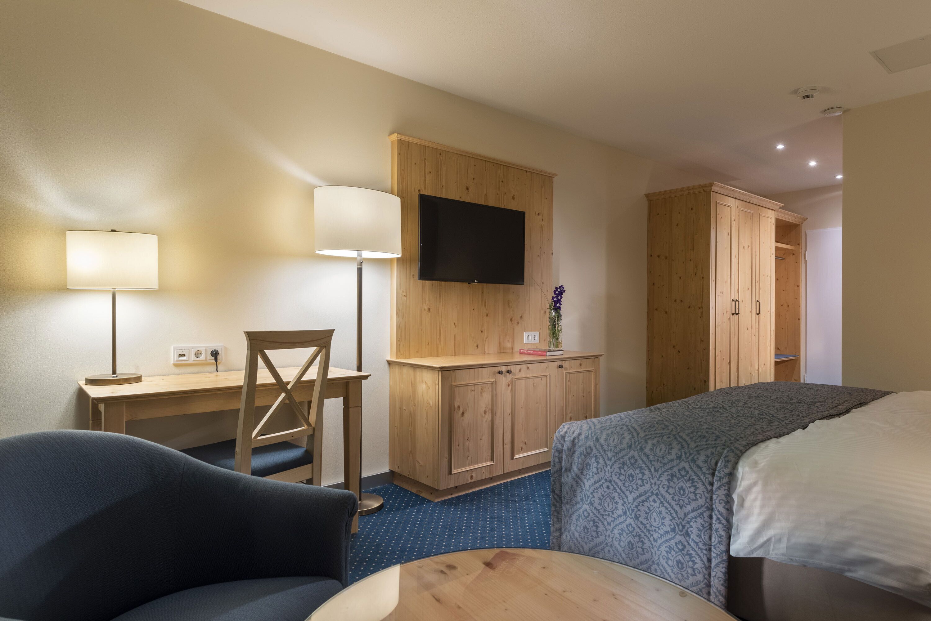 A hotel room with a desk, chair, TV, wardrobe, and two beds.