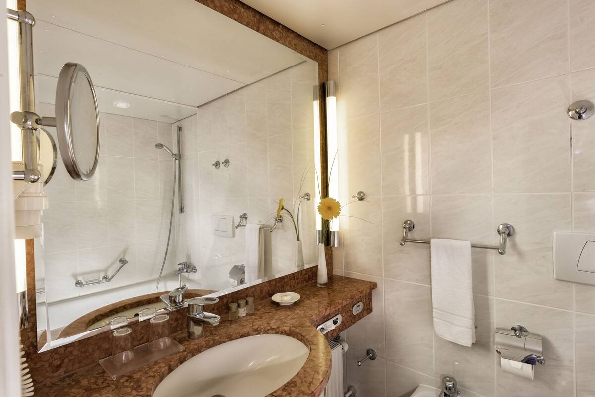 A modern bathroom with a large mirror, sink, and shower.