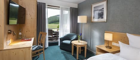 Une chambre d’hôtel comprenant un lit, un bureau avec une chaise, une télévision, une lampe et une vue sur l’extérieur.