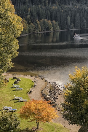 A lakeside view with a boat, lounge chairs, and a rocky shoreline.