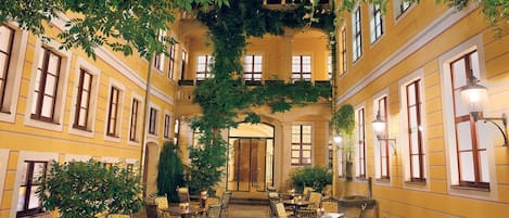 An indoor courtyard with yellow walls, multiple windows, and tables with chairs.