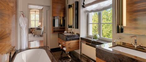 A modern bathroom with a bathtub, vanity, and a large window.