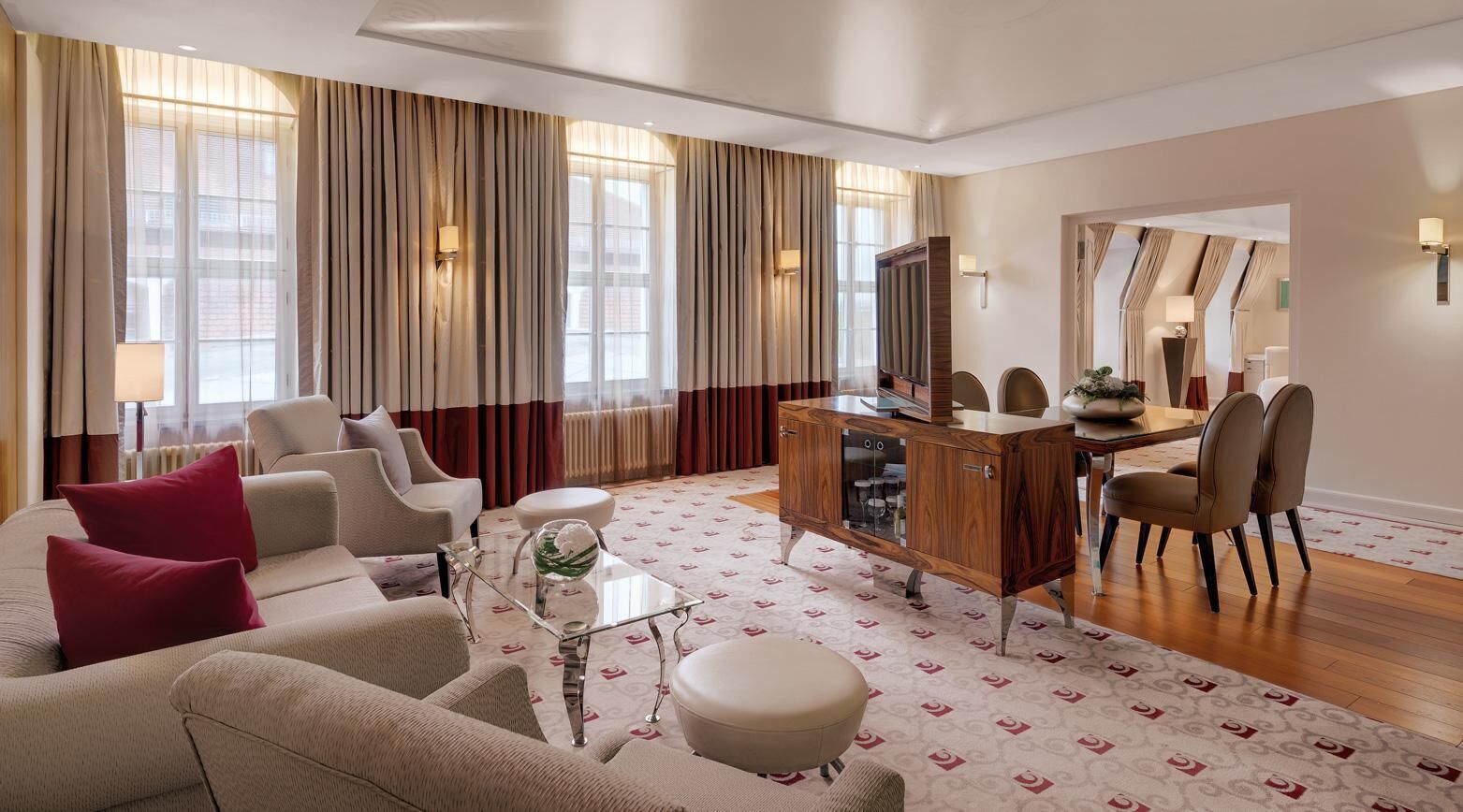 A spacious living room with a sofa set, a coffee table, and a dining area with chairs and a wooden cabinet.