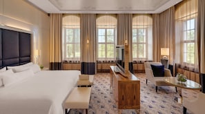 A hotel room with a large bed, a TV, a desk, a chair, and a glass coffee table. - Bilderberg Bellevue Hotel Dresden (Dresden)