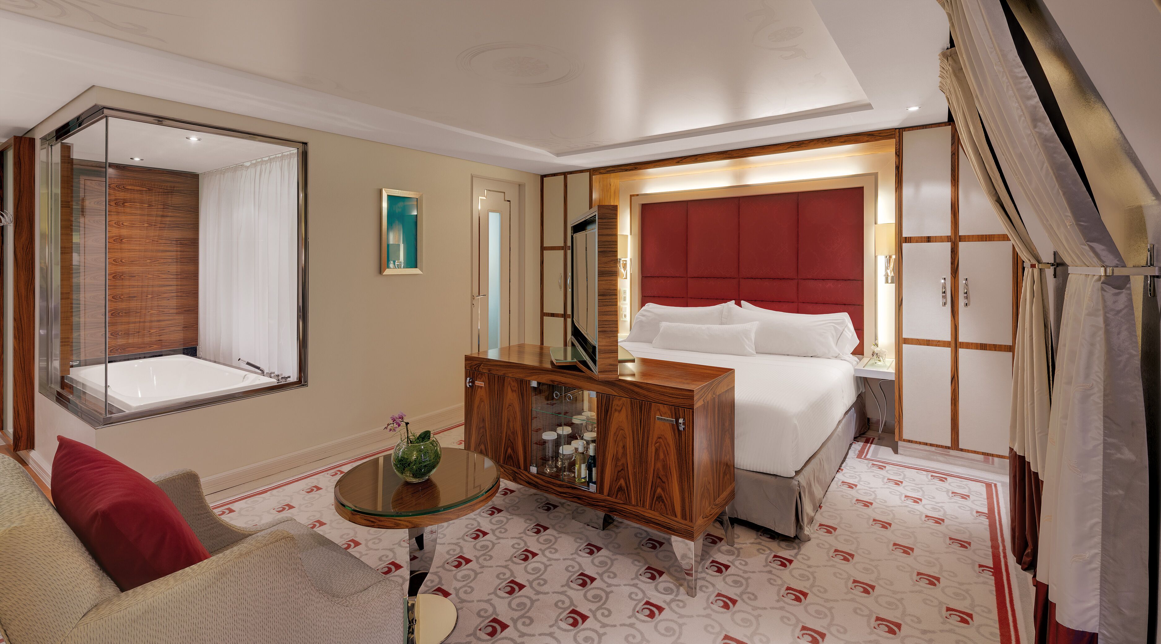 Ein Hotelzimmer mit einem großen Bett, einer hölzernen Kommode, einem Glastisch und einem Spiegel.