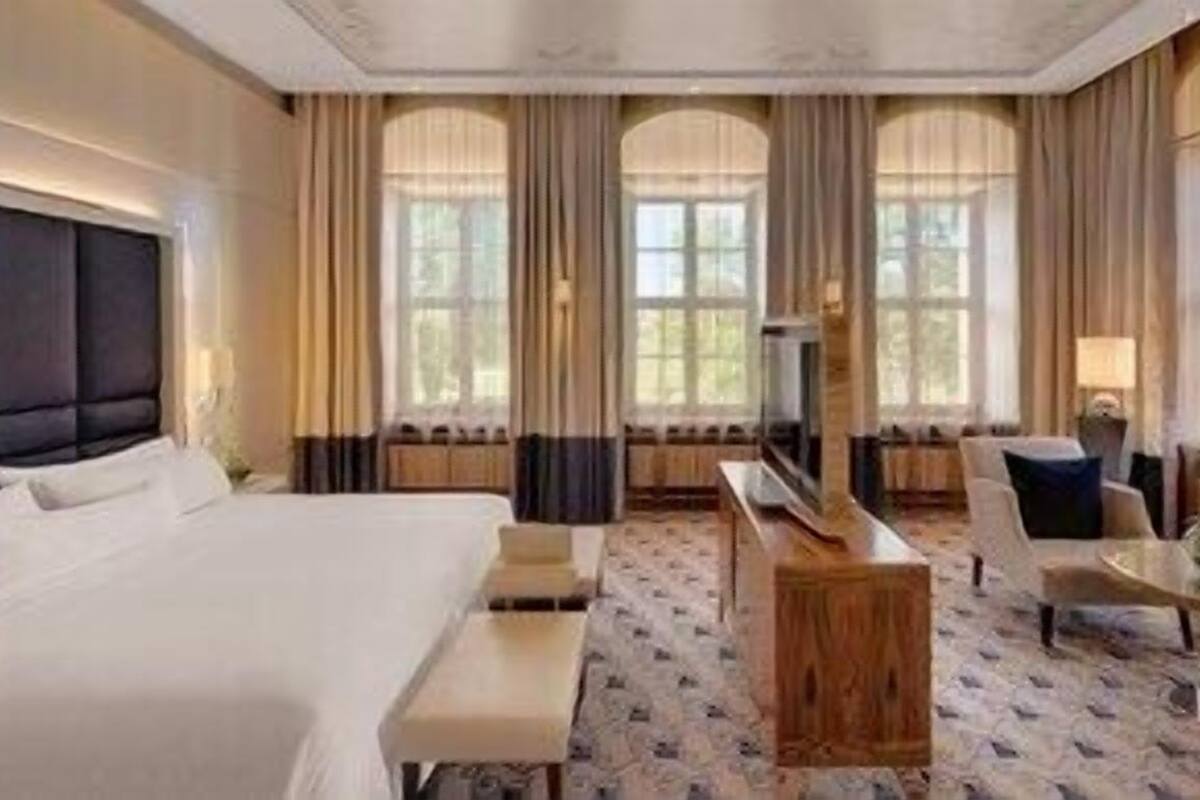 A hotel room with a large bed, a desk, a chair, and a sofa.