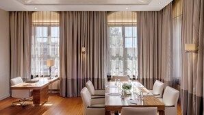 A conference room with a long table, chairs, and curtains.