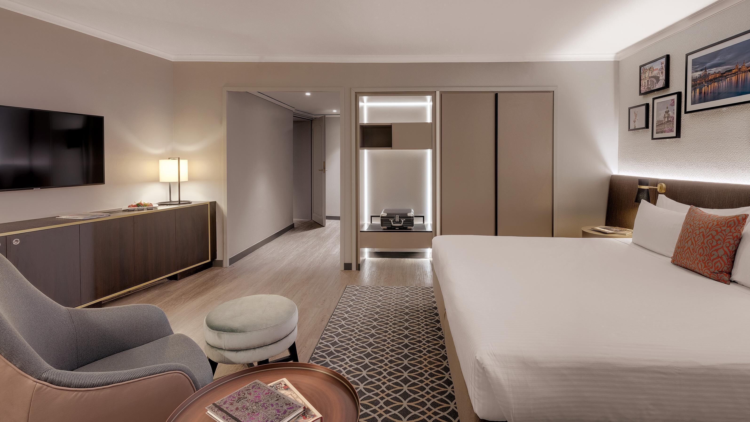 Ein Hotelzimmer mit Bett, Schreibtisch, Stuhl, Fernseher und einem kleinen Tisch.