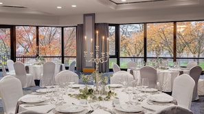 A banquet hall with round tables set for a formal event, large windows offering a view of autumn trees, and a candelabra centerpiece. - Bilderberg Bellevue Hotel Dresden (Dresden)