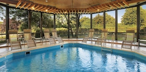 Un área de piscina con sillones de descanso y una pérgola de madera.