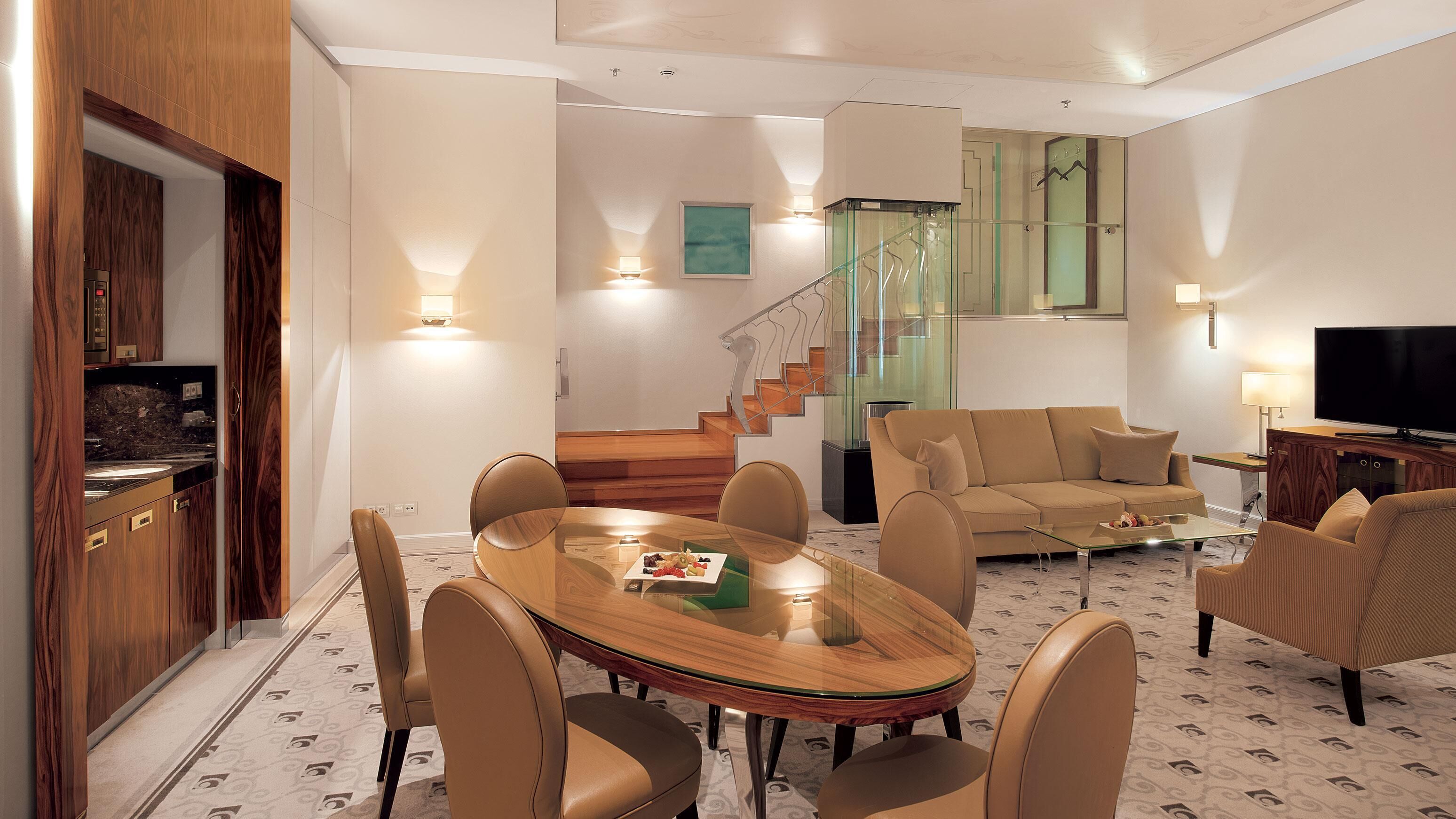 Una sala de estar moderna con una mesa de comedor de vidrio, sillas de cuero, un sofá y un televisor.