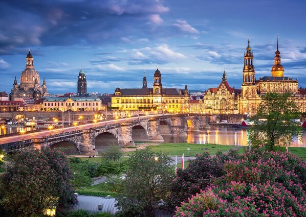 Un paisaje urbano histórico con una catedral destacada y un puente sobre un río.