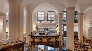 A bar area with a long counter, multiple chairs, and a bar stocked with bottles.