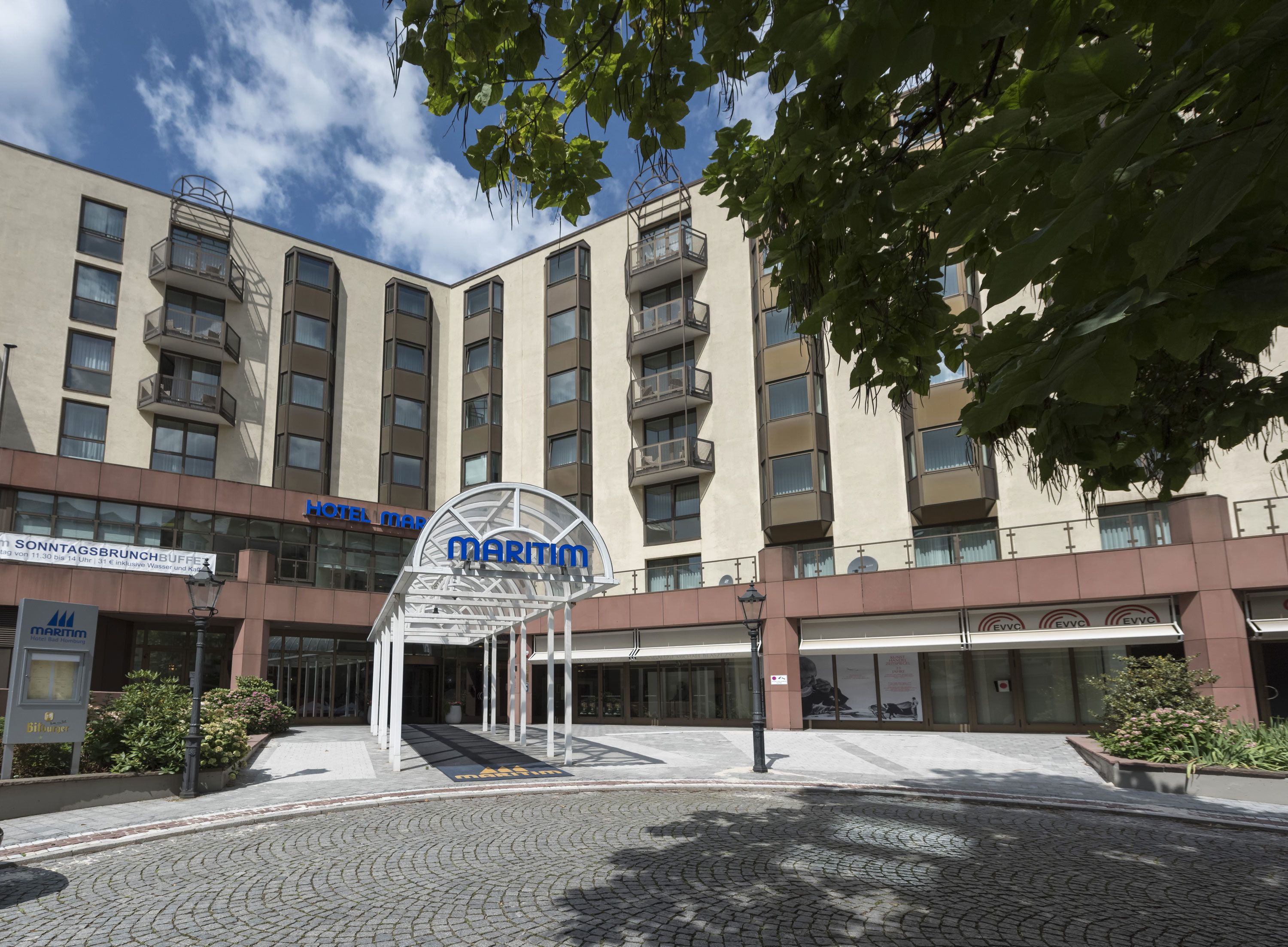 Um hotel com uma placa grande 'Maritim', várias varandas e uma área de entrada com calçada de pedra.