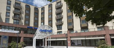 Un hotel con un llamativo letrero 'Maritim', varios balcones y una zona de entrada adoquinada.