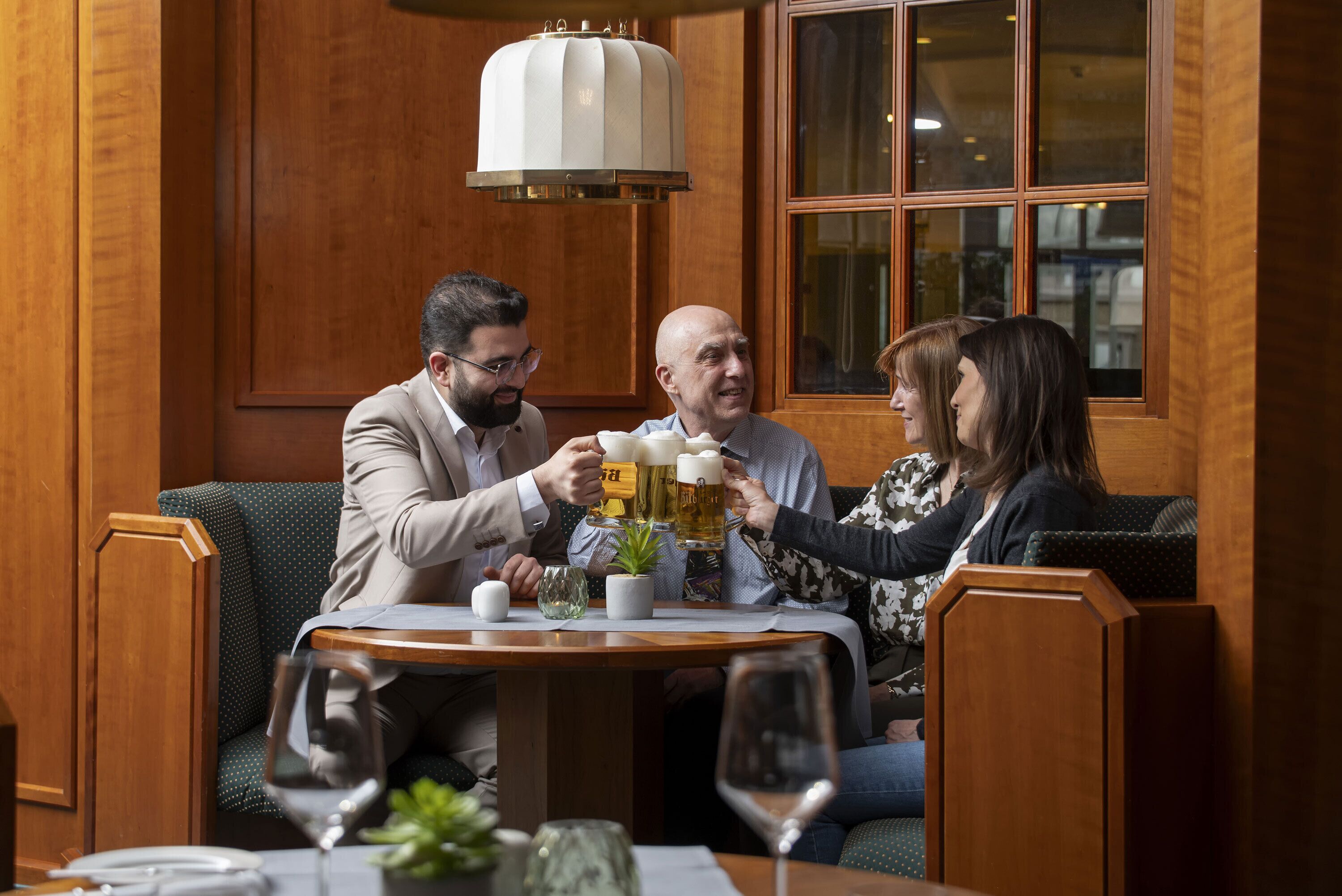 Un grupo de personas sentadas en una mesa de madera en un restaurante con un ventanal grande al fondo.