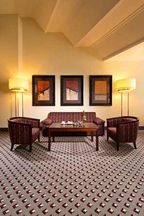 A hotel room with a patterned carpet, a sofa set, two armchairs, a coffee table, and three framed artworks on the wall. - Maritim Hotel Bad Homburg (Bad Homburg v.d. Hoehe)