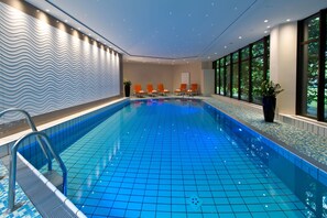 An indoor swimming pool with a tiled floor, a pool ladder, and several lounge chairs along the wall. - Maritim Hotel Bad Homburg (Bad Homburg v.d. Hoehe)
