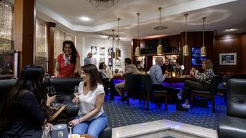 Rebedor d'hotel amb seients de cuir, zona de bar i obra d'art a les parets.