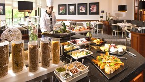 Montaje de bufé con diferentes alimentos y un cocinero al fondo.