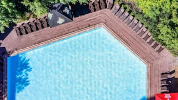 Vista aérea de una piscina con sillones de descanso y sombrillas.