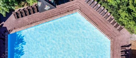 Vista aérea de una piscina con sillones de descanso y sombrillas.