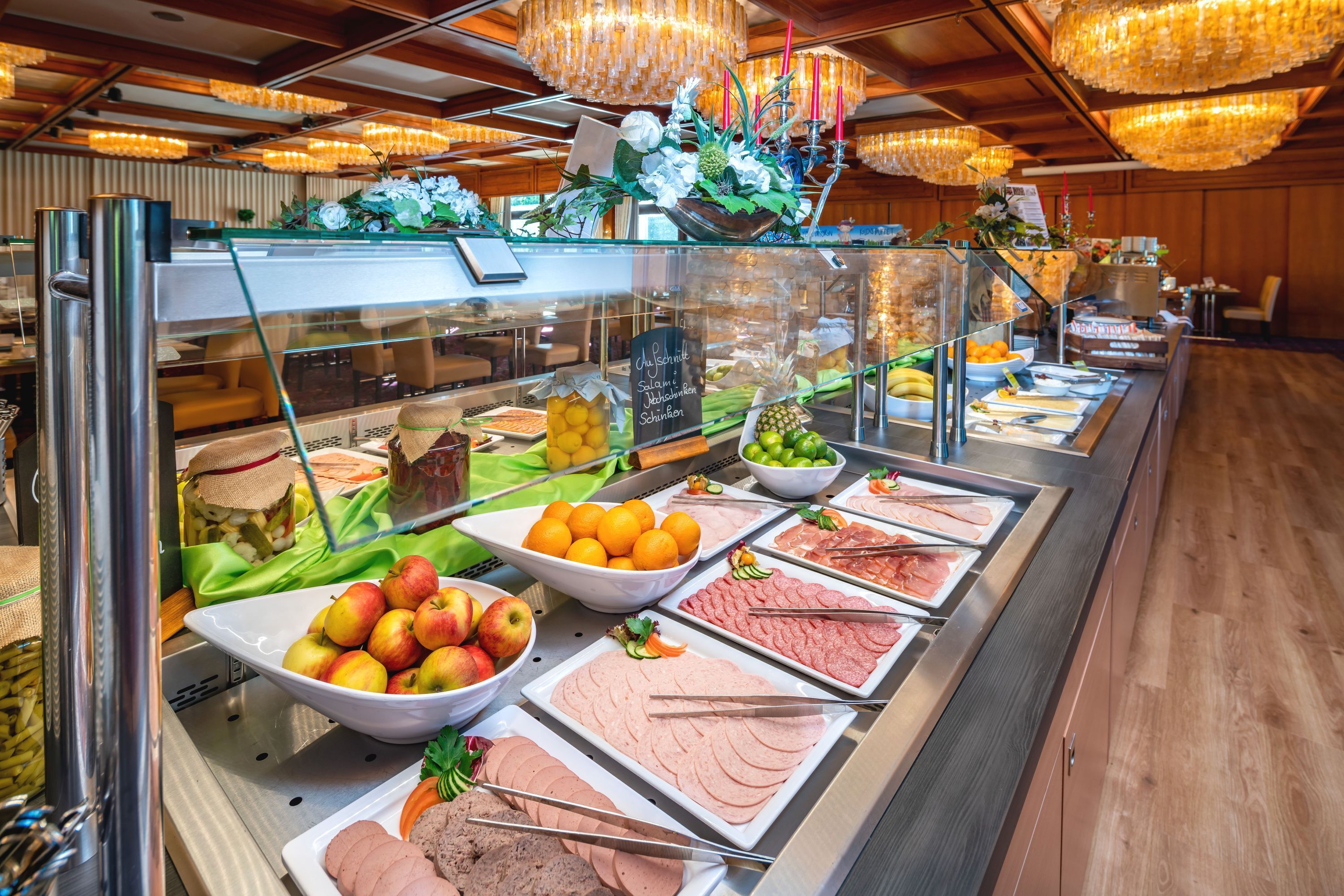 A buffet with various food items including fruits, vegetables, and meats.