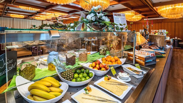 Un buffet proposant une variété d’aliments, notamment des fruits, des fromages et des pains.