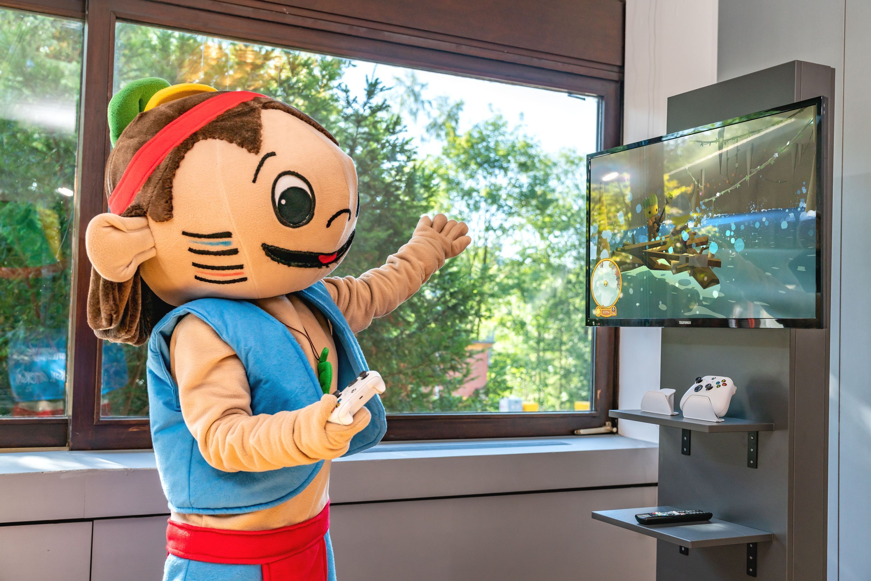 A person in a mascot costume standing in front of a television.