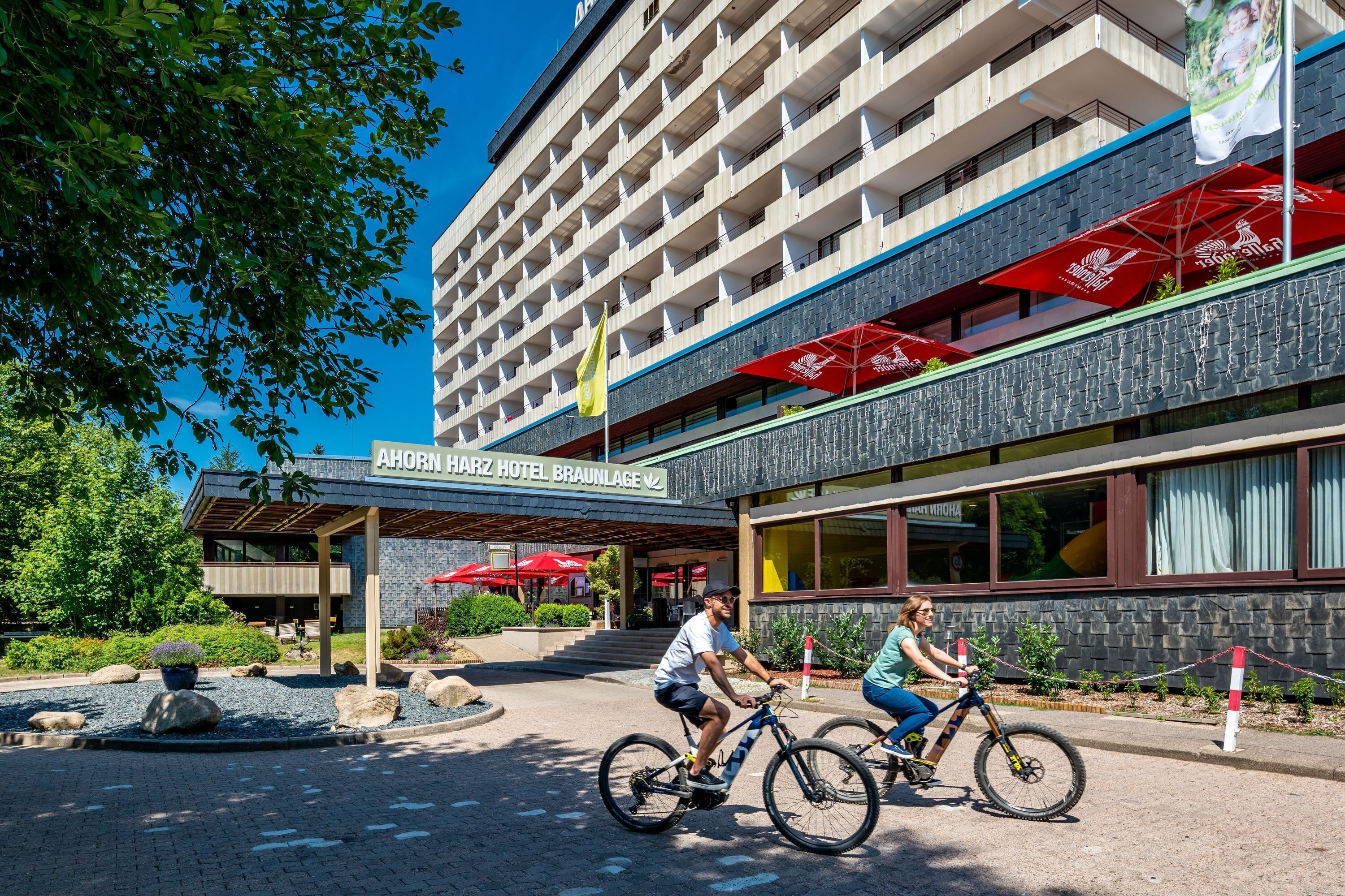 A hotel entrance with a modern design, outdoor seating, and a clear sky.