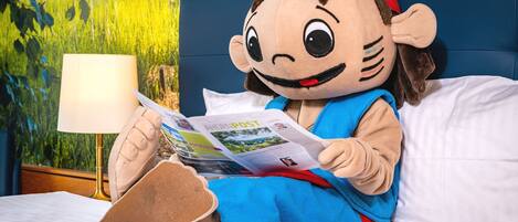 Un personaje de peluche sentado en una cama leyendo una revista.