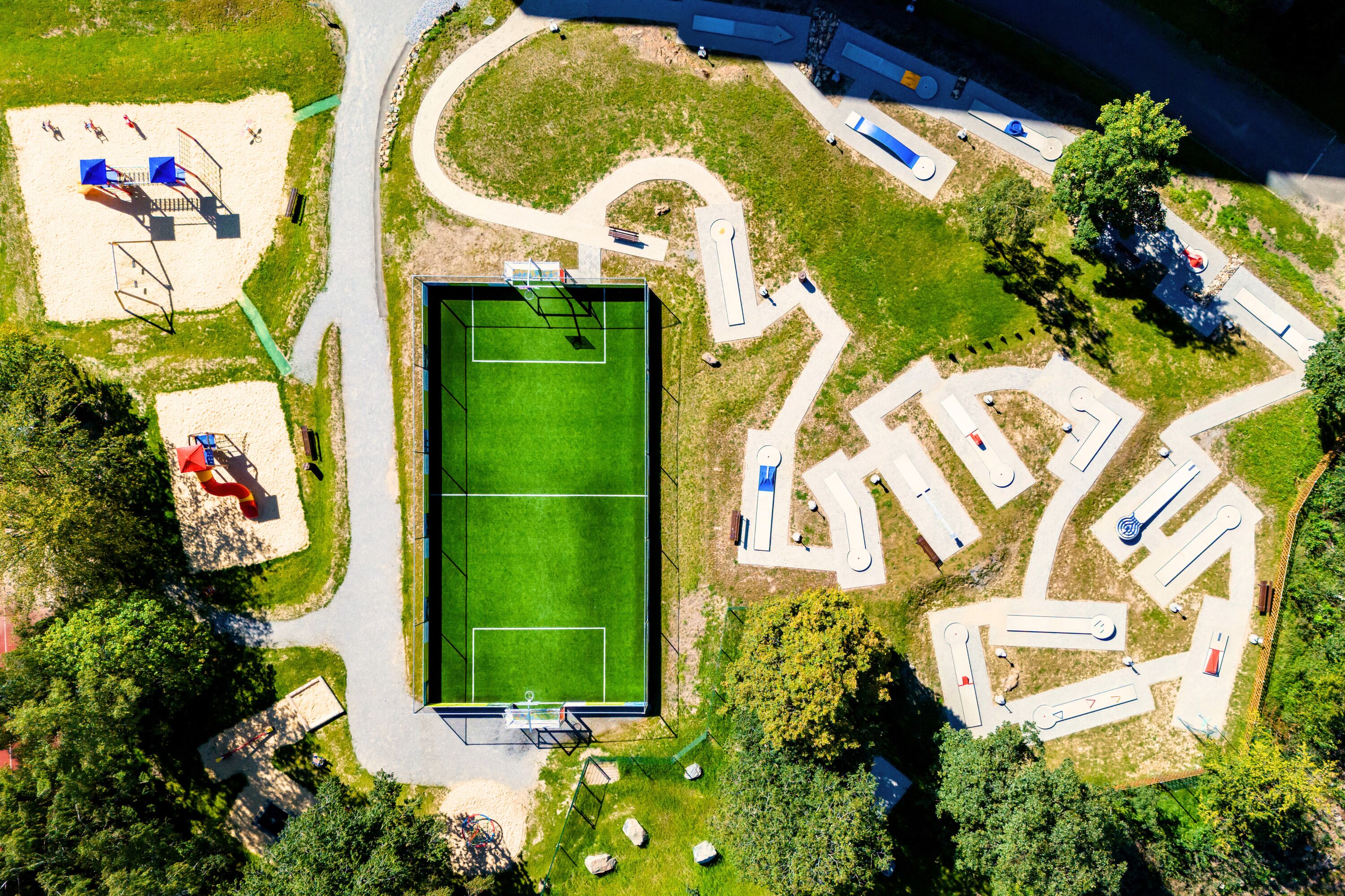 An aerial view of a sports complex with a tennis court, multiple sports fields, and parking areas.