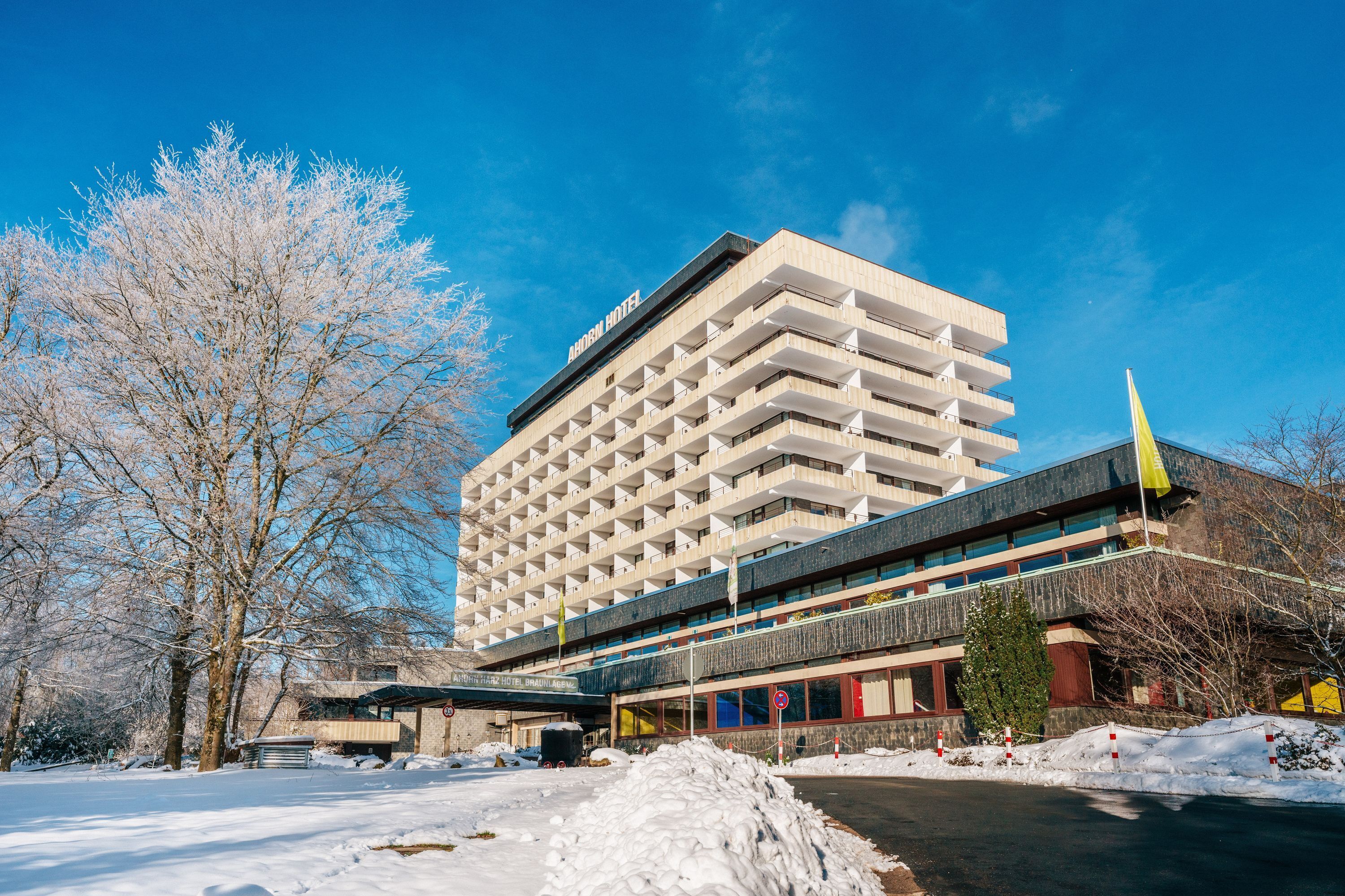 Un hôtel à plusieurs étages doté d’une architecture moderne, avec une entrée imposante et un espace de stationnement.