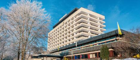 Un hôtel à plusieurs étages doté d’une architecture moderne, avec une entrée imposante et un espace de stationnement.
