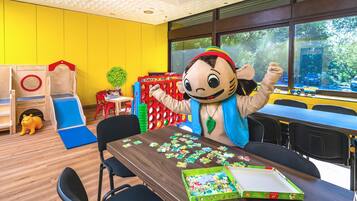 Ein Klassenzimmer mit einem großen Fenster, Holzspielgeräten und einer Maskotte.