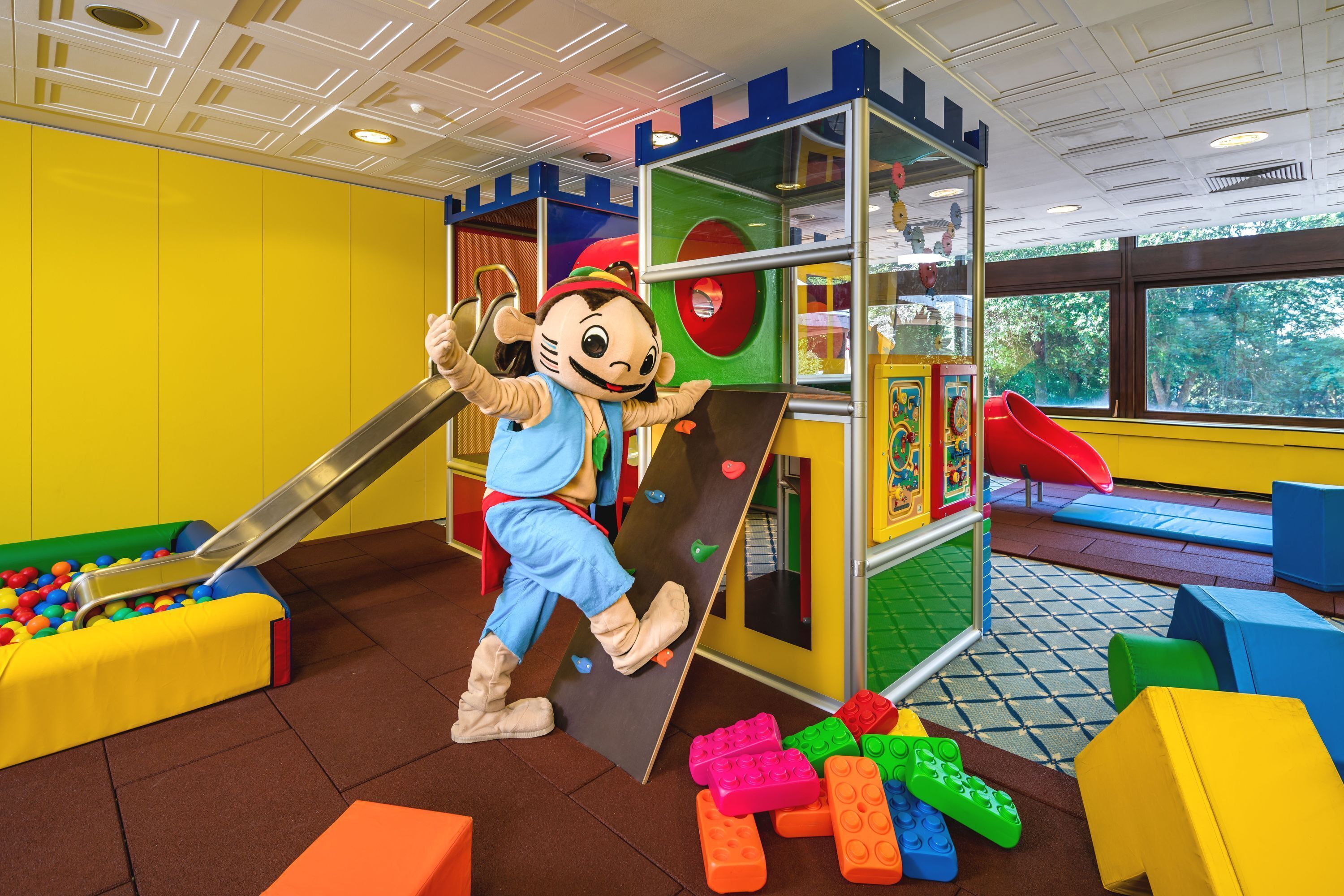 Un área de juegos con un tobogán, pared de escalar y bloques de construcción de colores.