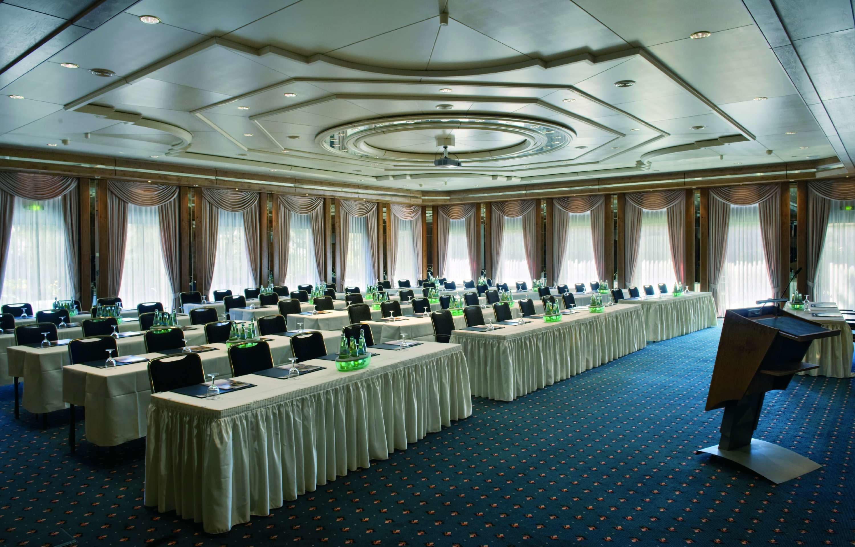 A conference room with long tables, chairs, and a podium.