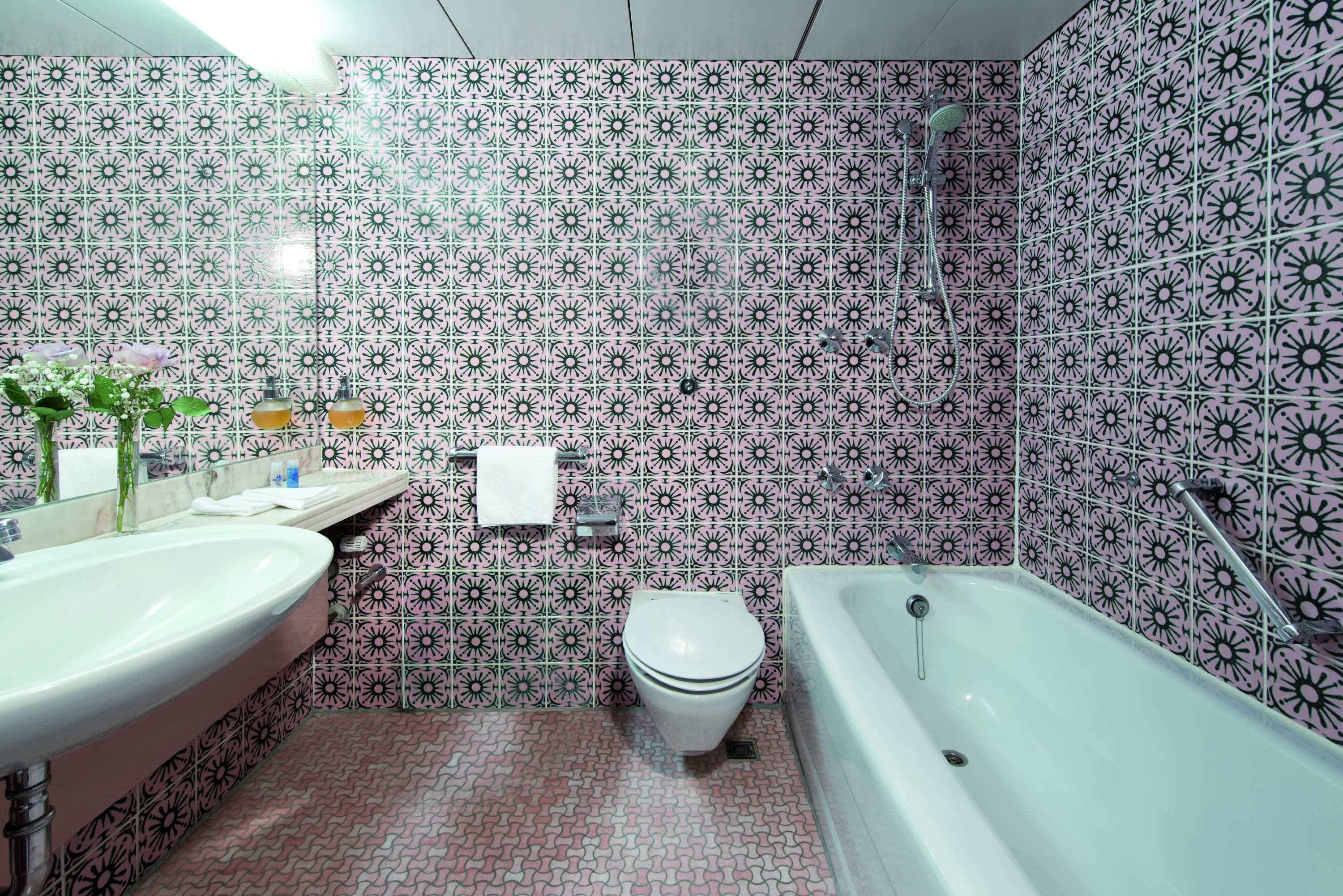 A bathroom with a sink, toilet, and bathtub, all with a patterned tile backsplash.