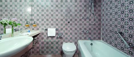 A bathroom with a sink, toilet, and bathtub, all with a patterned tile backsplash.