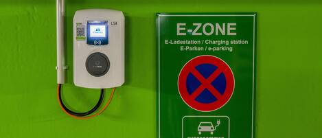 An electric vehicle charging station with a sign indicating it is an E-ZONE charging station.