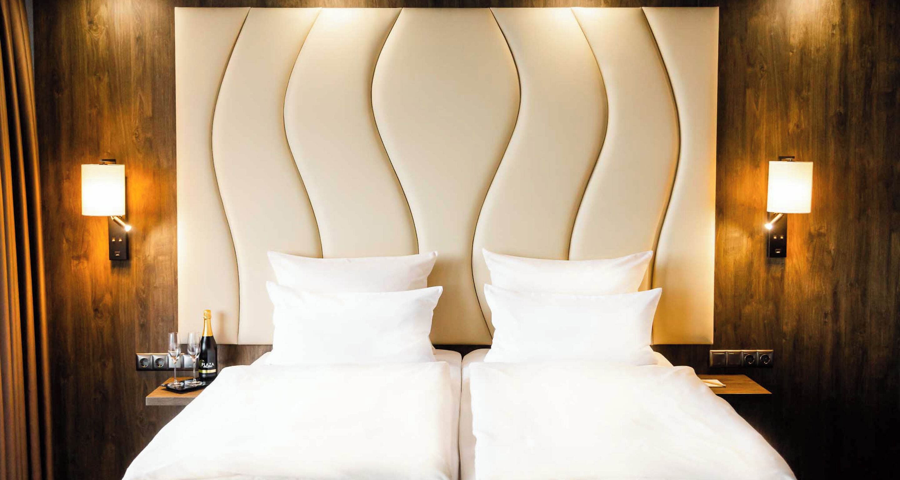 Una camera d'albergo con un letto grande, due comodini e lampade a parete.