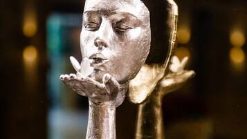 Eine Skulptur eines Gesichts mit ausgestreckter Hand, präsentiert auf einem schwarzen Sockel.