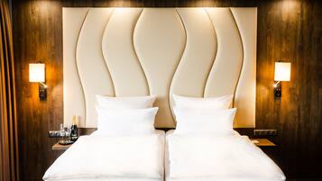 A double bed with a modern headboard, bedside lamps, and a nightstand with a bottle and glasses.
