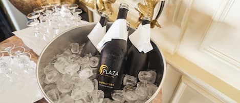 Een emmer met ijs en champagneflessen met de aanduiding 'Plaza Signature' in een luxe omgeving.